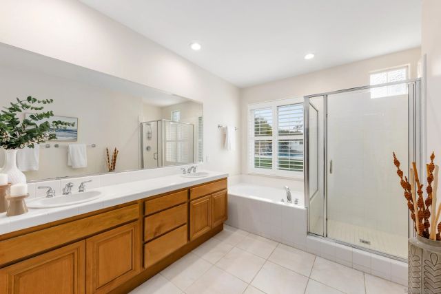 a spacious bathroom with a double vanity sink a large mirror and a bathtub