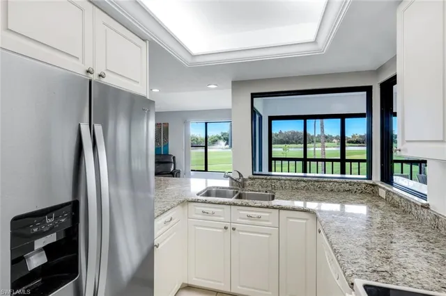 a view of a kitchen with granite countertop a refrigerator and a sink