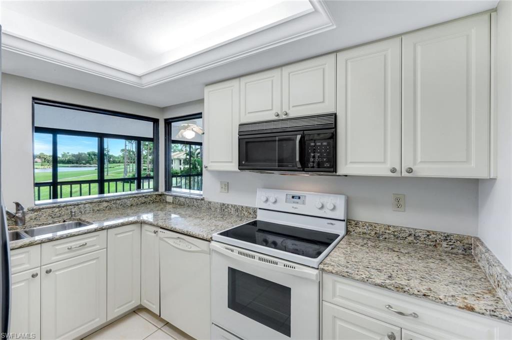 5585 Trailwinds Drive, Unit 326 Fort Myers, FL 33907 - Photo 10 of 37 a kitchen with granite countertop white cabinets stainless steel appliances and a sink