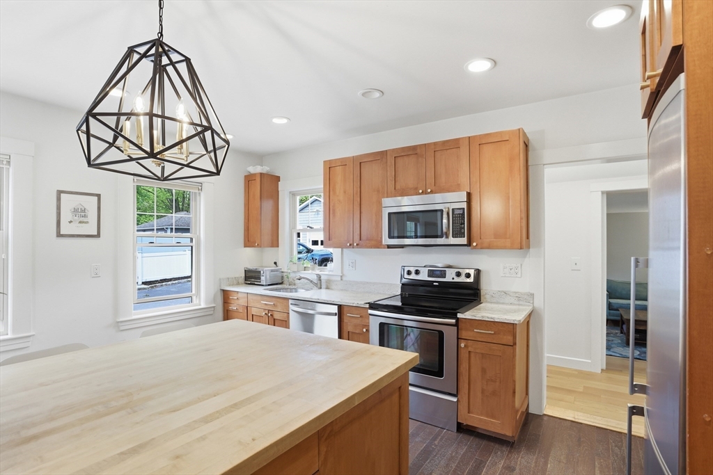 80 Concord Street Maynard, MA 01754 - Photo 6 of 29 a kitchen with stainless steel appliances a white stove top oven a sink dishwasher a dining table and chairs with wooden floor