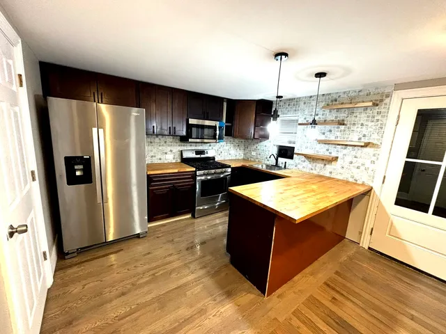 a kitchen with stainless steel appliances granite countertop a refrigerator a stove a sink and a microwave