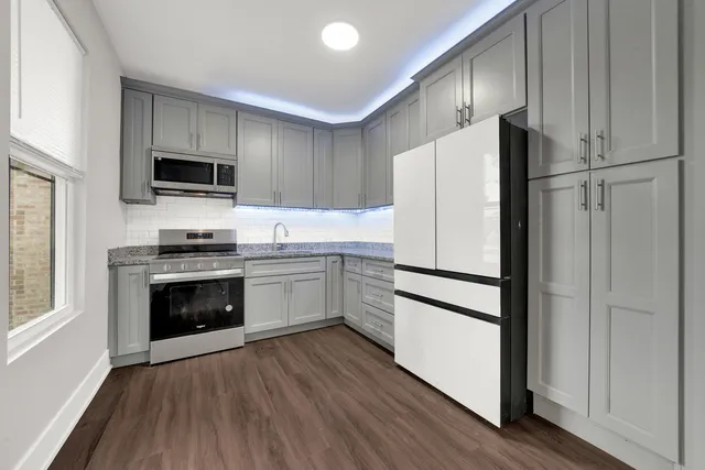 a kitchen with a refrigerator stove and wooden floor