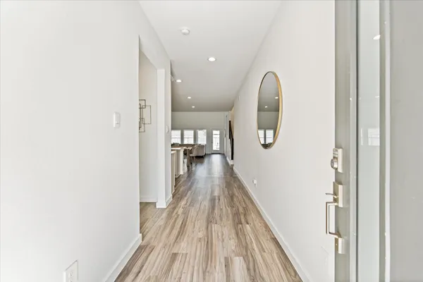 a view of a hallway with wooden floor and a bathroom