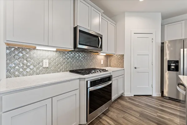a kitchen with stainless steel appliances white cabinets and a stove top oven