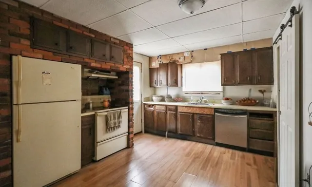 a kitchen with a refrigerator stove and sink with wooden floor