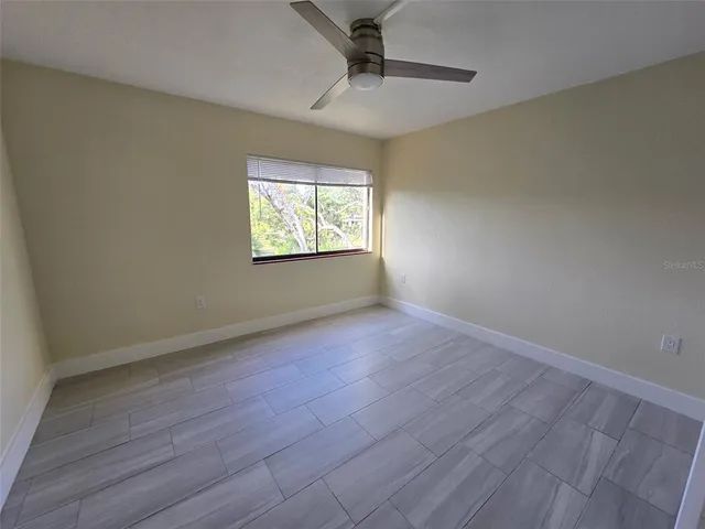 an empty room with wooden floor ceiling fan and windows