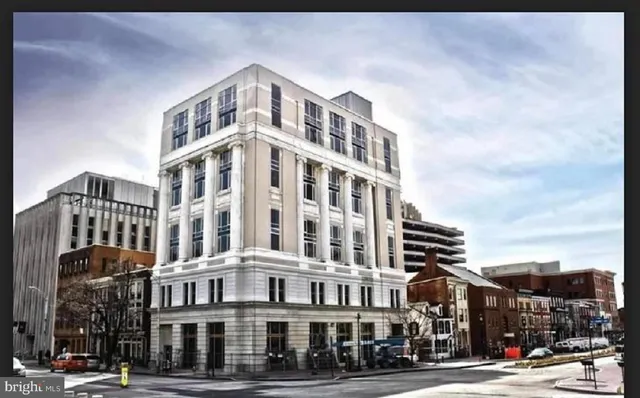 a front view of a building with lot of cars and trees