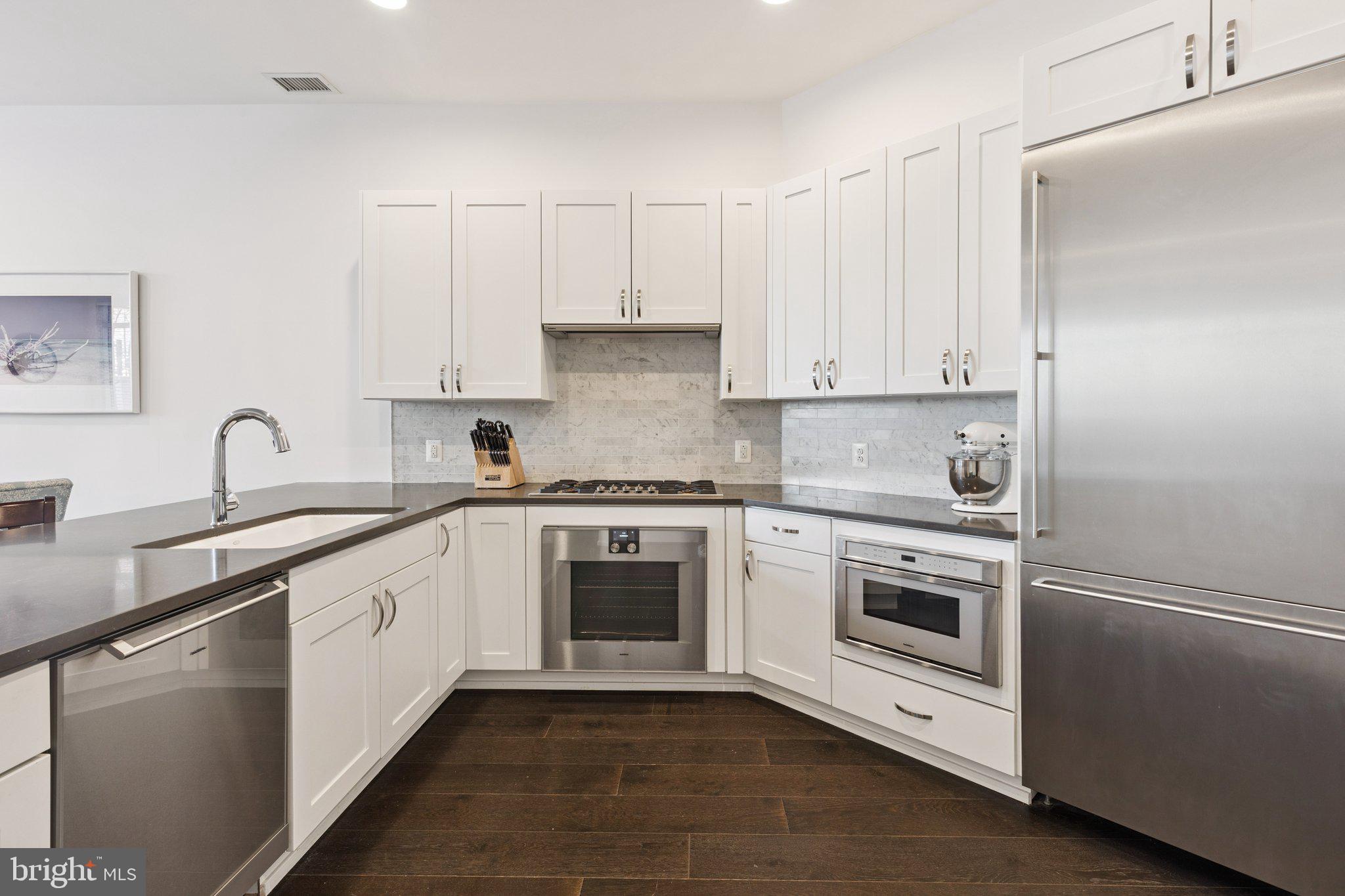 410 South Front Street, Unit 108 Philadelphia, PA 19147 - Photo 9 of 34 a white kitchen with granite countertop white cabinets and white appliances