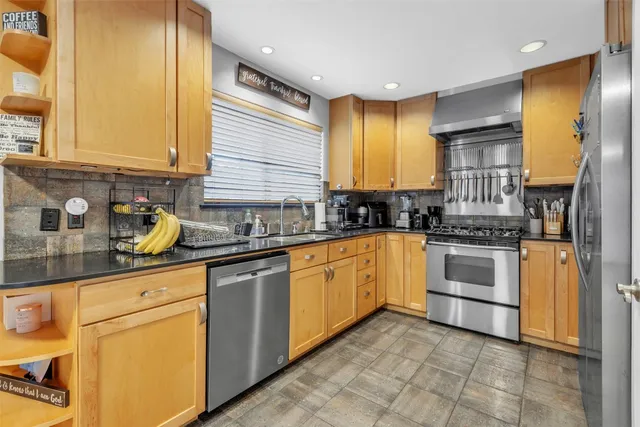 a kitchen with stainless steel appliances granite countertop a stove a sink and a refrigerator