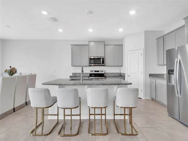 a kitchen with stainless steel appliances granite countertop a sink a stove a microwave a counter top space and cabinets