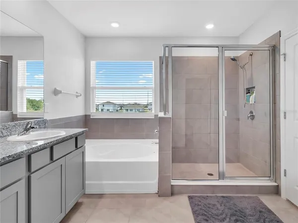 a bathroom with a granite countertop bathtub a sink and a large mirror