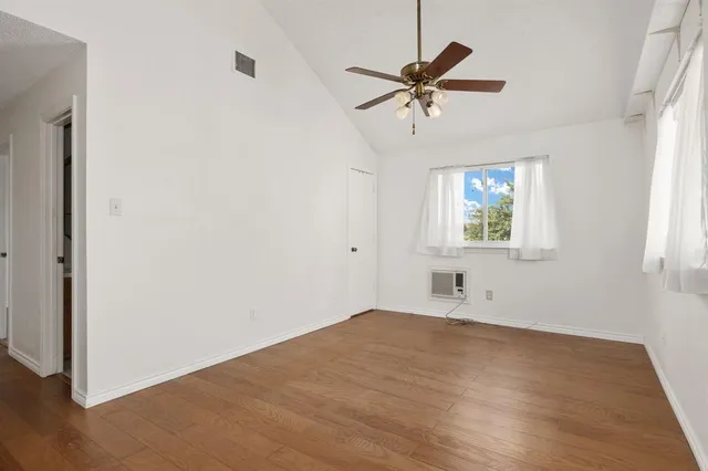 a view of empty room with wooden floor and fan