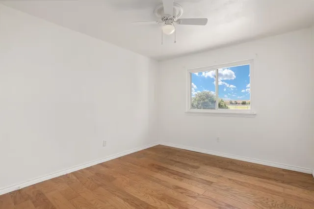 an empty room with wooden floor and ceiling fan