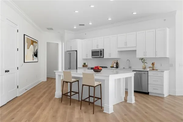 a kitchen with stainless steel appliances a white stove top oven cabinets a dining table and chairs with wooden floor