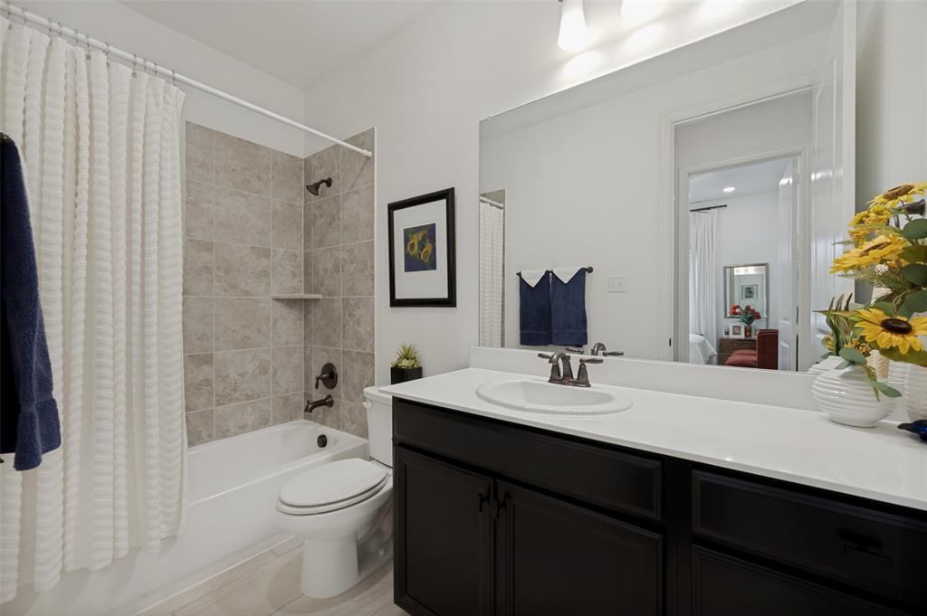 7821 Kentmere The Colony, TX 75056 - Photo 20 of 40 The well-appointed secondary bathroom features an oversized vanity with generous counter space and storage, along with a classic tub and shower combination finished with elegant tile surround. Bright, functional, and thoughtfully designed, it's perfect for family members and guests alike.