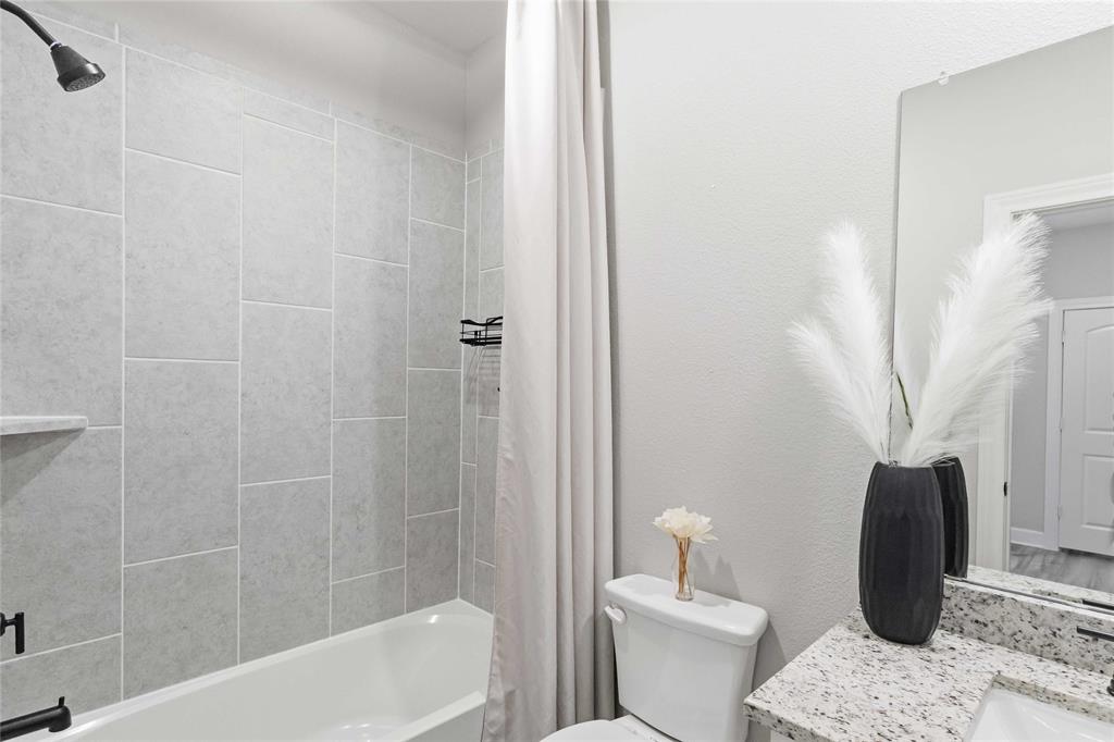 1012 Calhoun Drive Anna, TX 75409 - Photo 26 of 39 Bathroom featuring a white tub with black fixtures, light gray subway tile surround, and a built-in shower shelf