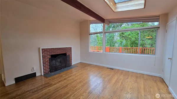 an empty room with wooden floor fireplace and windows