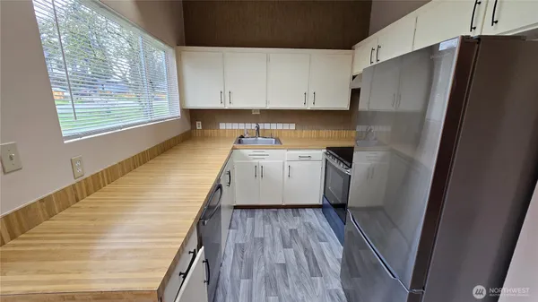 a kitchen with granite countertop a refrigerator a sink and white cabinets