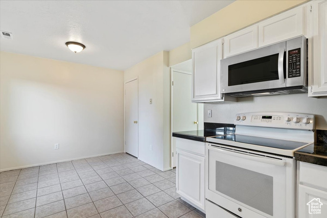 947 Canyon Road South, Unit 15 Ogden, UT 84404 - Photo 7 of 22 Kitchen featuring white range with electric stovetop, stainless steel microwave, white cabinets, and light tile patterned floors