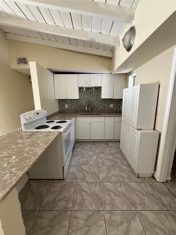a kitchen with granite countertop a refrigerator and a stove top oven