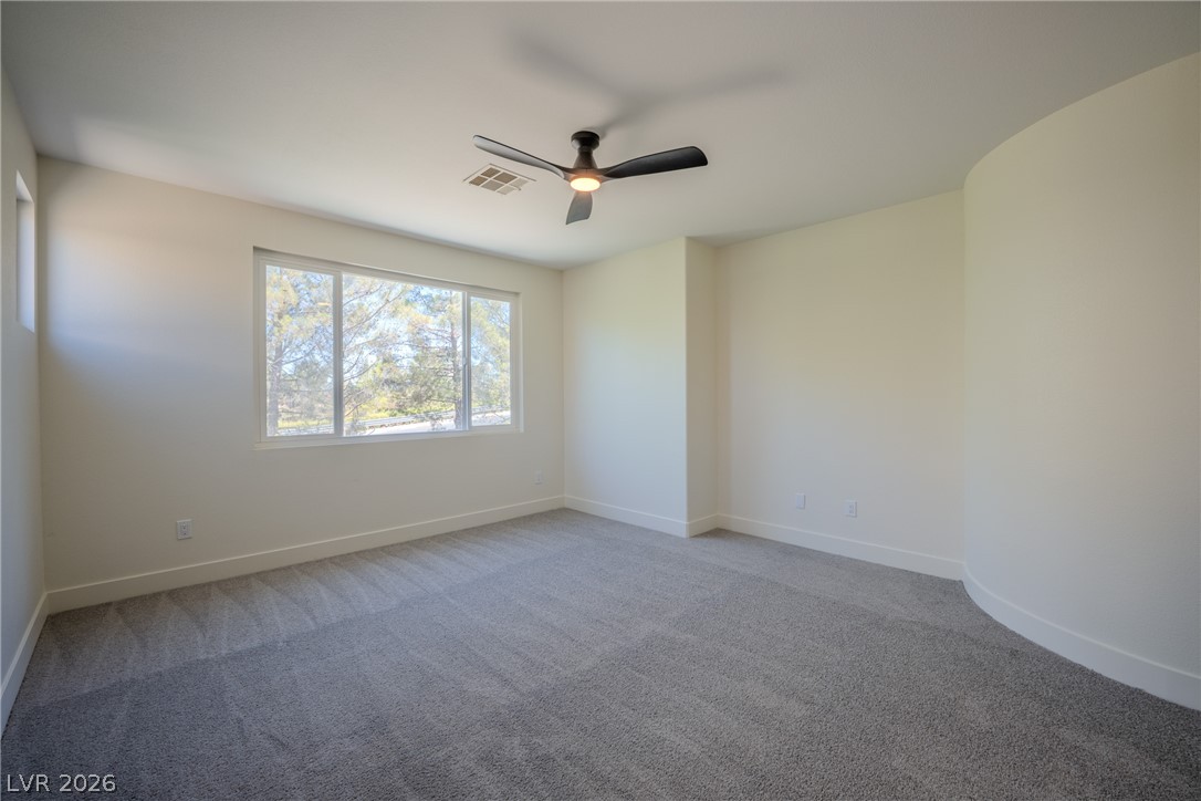 1832 Spring Summit Lane Las Vegas, NV 89134 - Photo 33 of 52 Well-lit sleeping quarters with a ceiling fan, plush gray carpet, and views of surrounding trees.