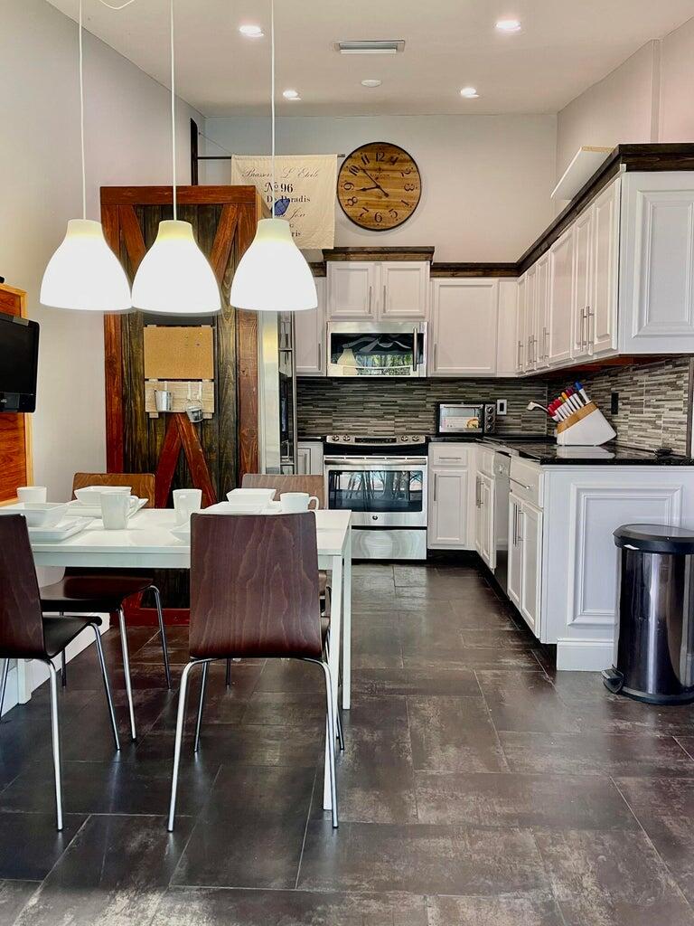 1259 Denlow Lane Royal Palm Beach, FL 33411 - Photo 16 of 40 a kitchen with stainless steel appliances granite countertop a stove top oven a sink a dining table and chairs