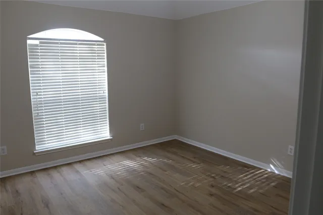 an empty room with wooden floor and a window