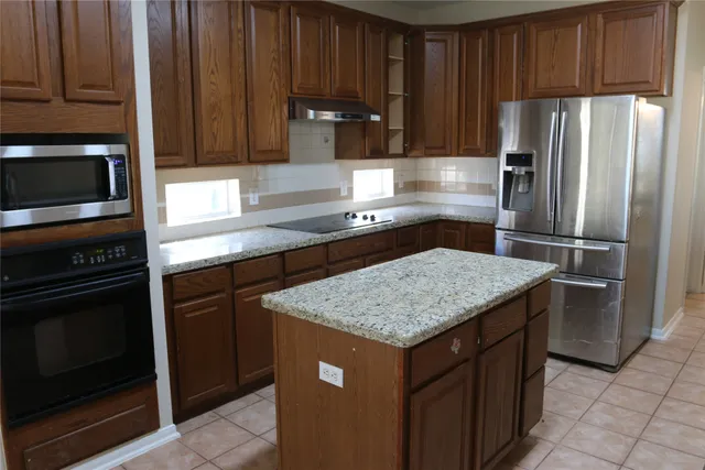 a kitchen with granite countertop a refrigerator and a sink