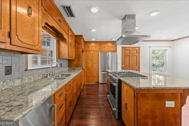 a large kitchen with stainless steel appliances granite countertop a refrigerator a sink dishwasher a stove and white countertops with wooden floor
