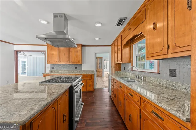 a large kitchen with stainless steel appliances wooden floors and large window