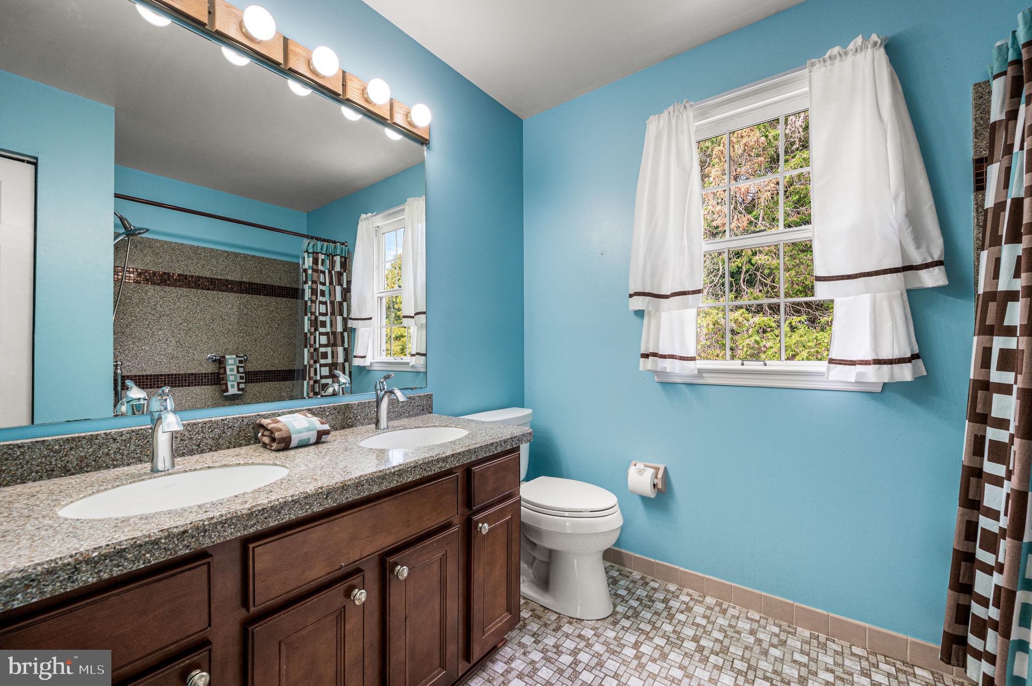23 East Knowlton Road Media, PA 19063 - Photo 29 of 40 a bathroom with a granite countertop sink toilet a mirror and a window