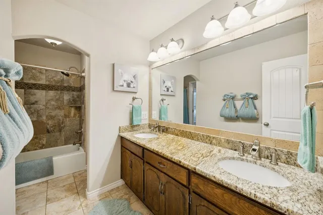 a bathroom with a granite countertop double vanity sink and a mirror