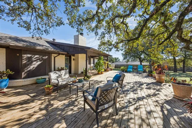 a view of a patio with table and chairs potted plants and large tree