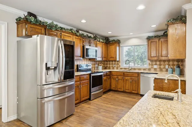 a kitchen with stainless steel appliances granite countertop a refrigerator a sink and a stove