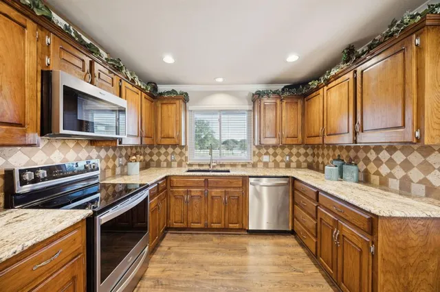 a kitchen with stainless steel appliances granite countertop wooden cabinets a stove top oven a sink and dishwasher