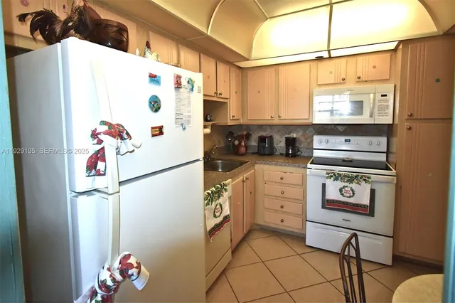 a kitchen with a refrigerator a stove a sink dishwasher and white cabinets with wooden floor