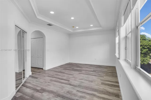 a view of empty room with wooden floor and fan