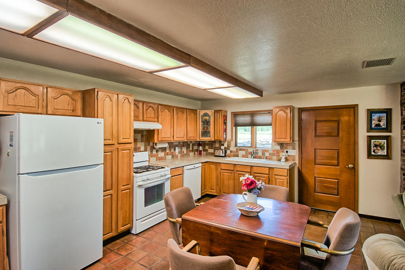 9375 Thatcher Mill Road Shingletown, CA 96088 - Photo 5 of 23 a kitchen with a refrigerator a stove and a dining table with wooden floor