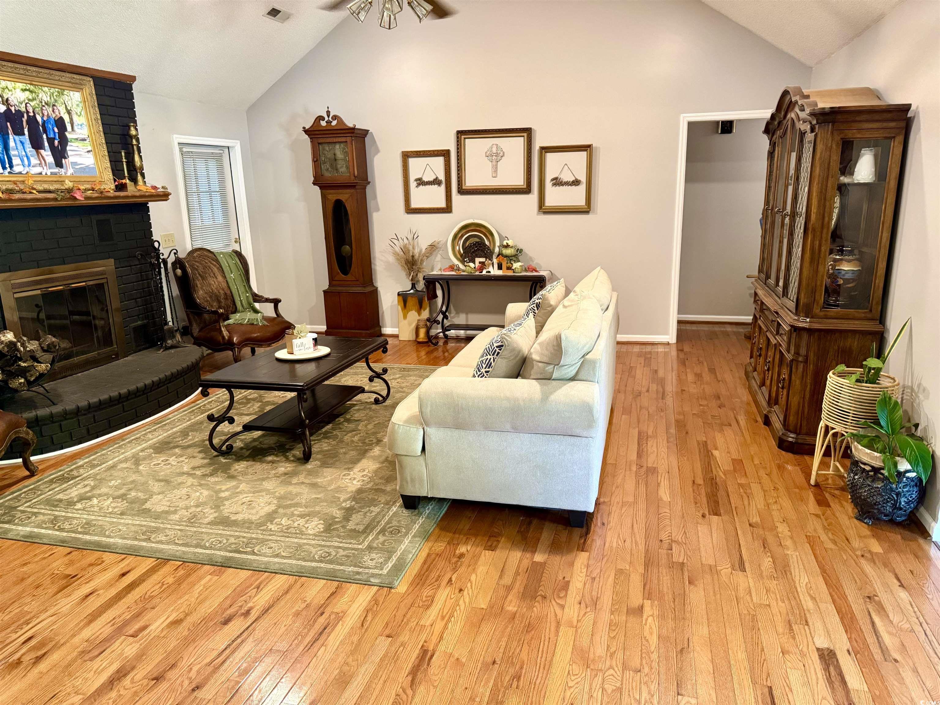40 Governor Boone Lane Georgetown, SC 29440 - Photo 4 of 33 Living area with vaulted ceiling, hardwood / wood-style floors, ceiling fan, and a fireplace