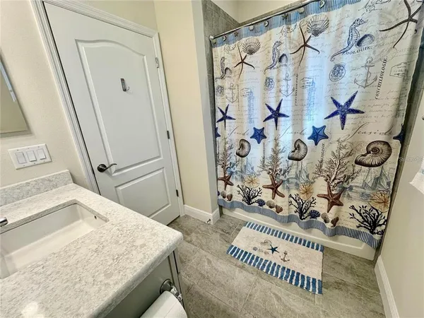 a bathroom with a granite countertop sink and a shower