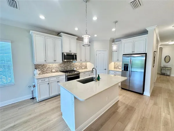 a kitchen with kitchen island a sink a stove a refrigerator and white cabinets