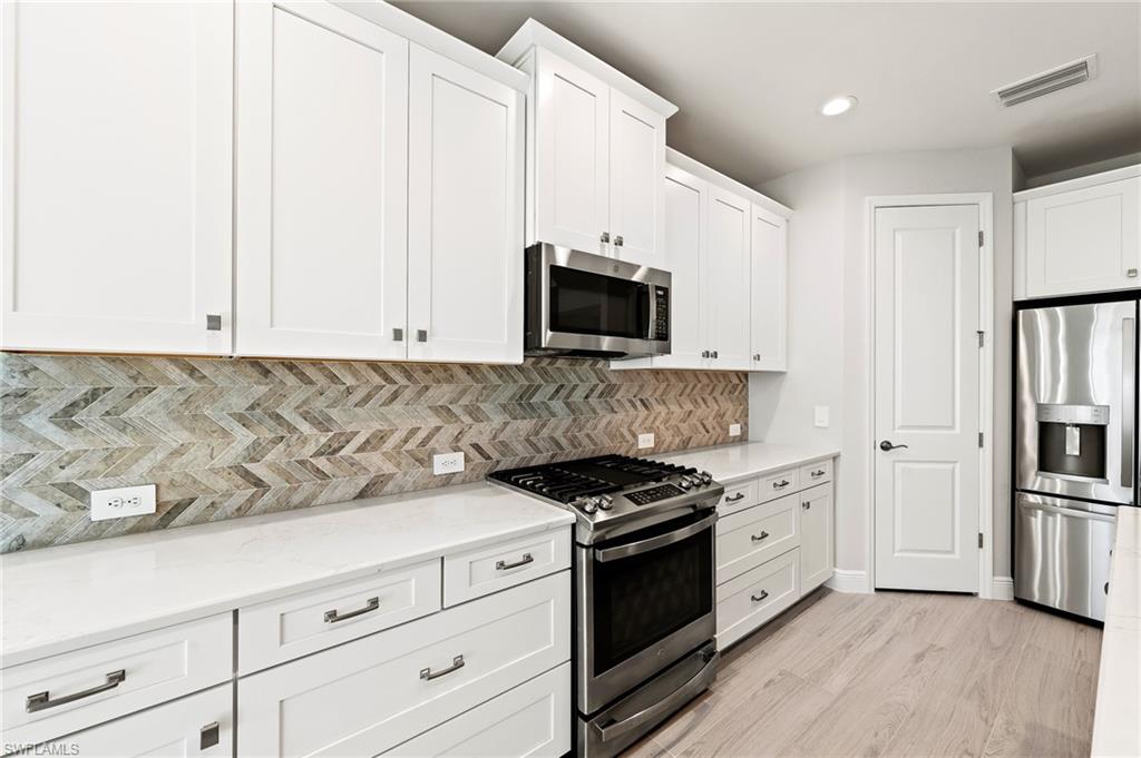 3952 Pegasus Way Naples, FL 34120 - Photo 12 of 50 a kitchen with granite countertop white cabinets and stainless steel appliances