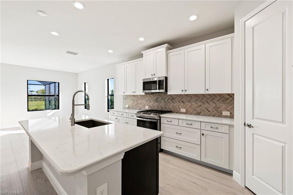 3952 Pegasus Way Naples, FL 34120 - Photo 14 of 50 a kitchen with granite countertop white cabinets and stainless steel appliances