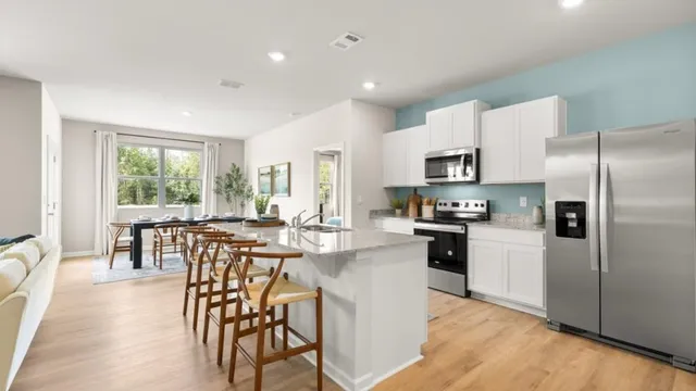 a kitchen with stainless steel appliances granite countertop a stove a refrigerator a kitchen island a stove and a dining table with wooden floor