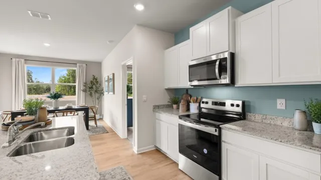 a kitchen with granite countertop a sink a stove top oven and cabinetry