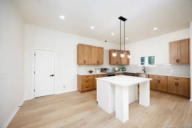 a kitchen with a stove a sink a kitchen island with wooden cabinets and wooden floor