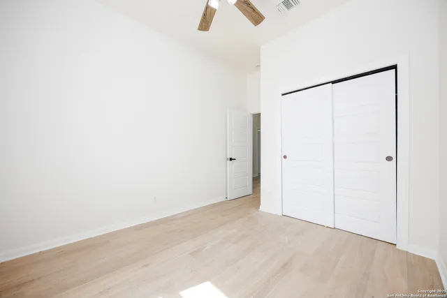 an empty room with ceiling fan and window