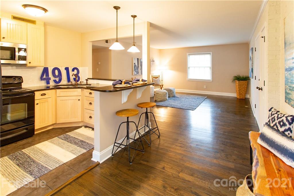 4913 Park Road, Unit D Charlotte, NC 28209 - Photo 4 of 32 a view of a kitchen with kitchen island granite countertop wooden floors and a sink
