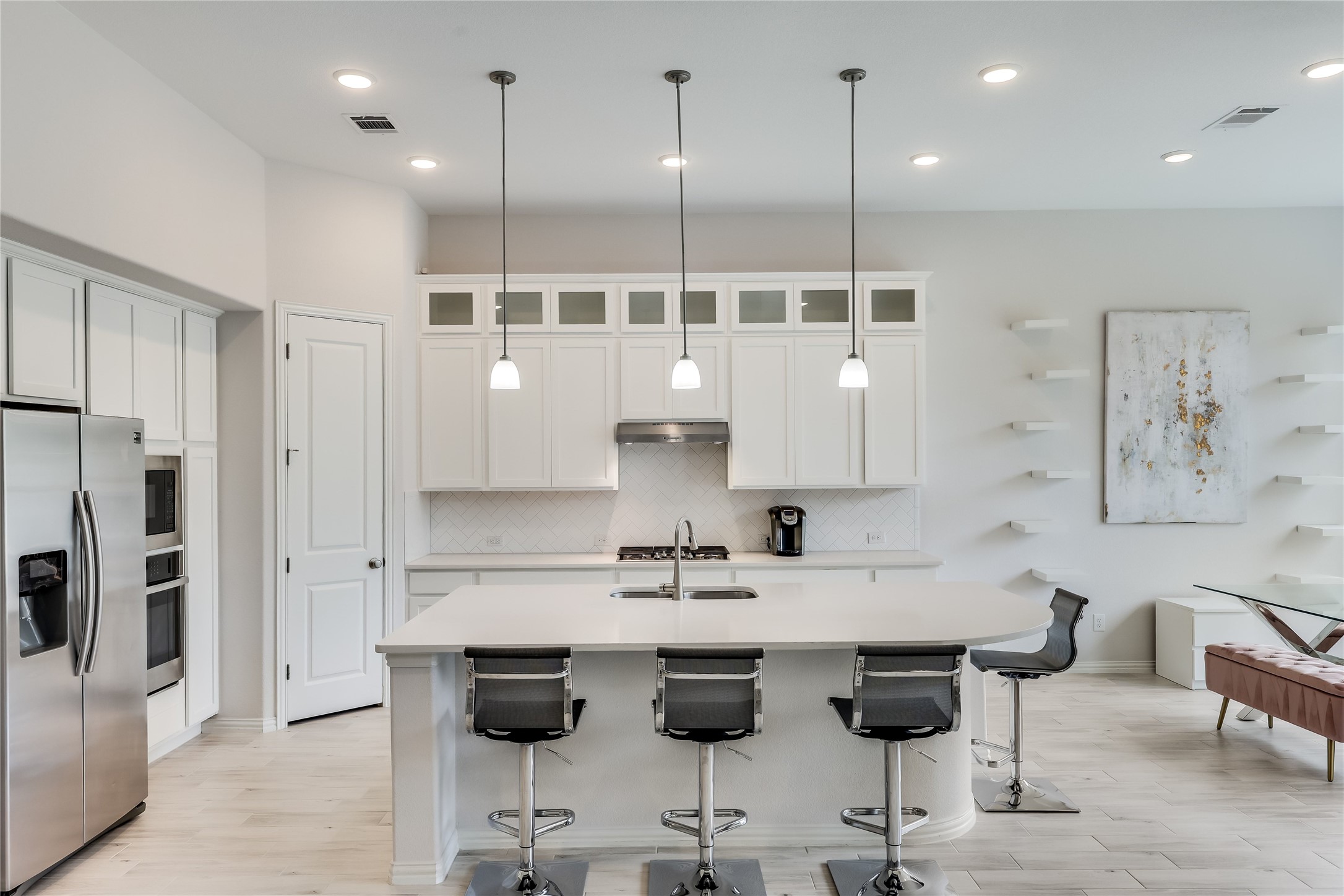 7705 Pace Ravine Drive Lago Vista, TX 78645 - Photo 8 of 40 Kitchen with stainless steel appliances, light wood-style flooring, white cabinetry, and hanging light fixtures