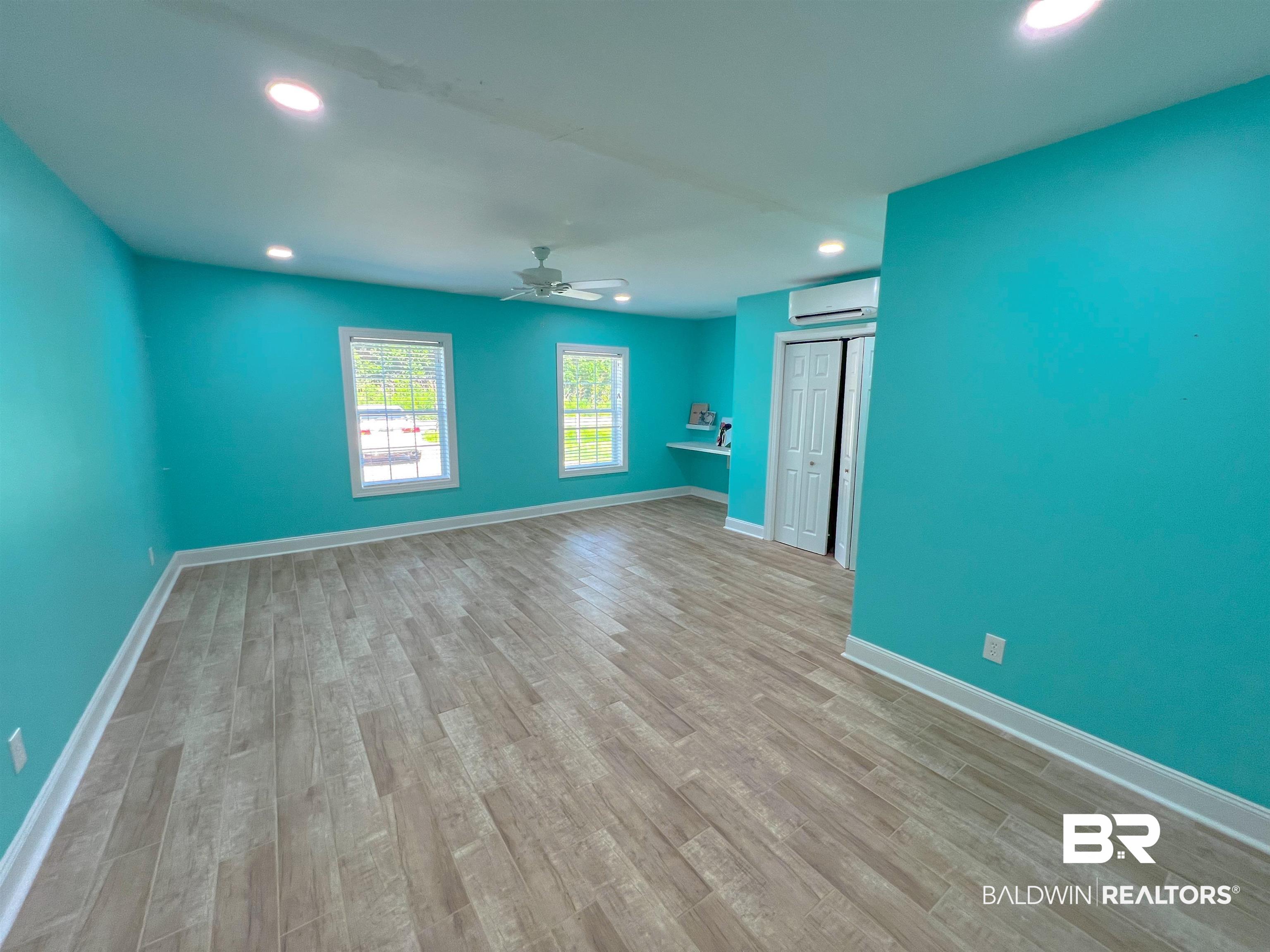 1200 South Juniper Street Foley, AL 36535 - Photo 13 of 23 Unfurnished living room with a wall mounted AC, hardwood / wood-style flooring, and ceiling fan